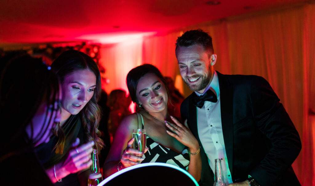 Guests posing together at a ring light photo booth during a party