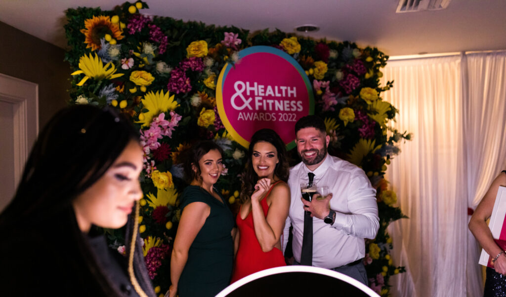 Guests posing in front of a floral backdrop at a wellness event
