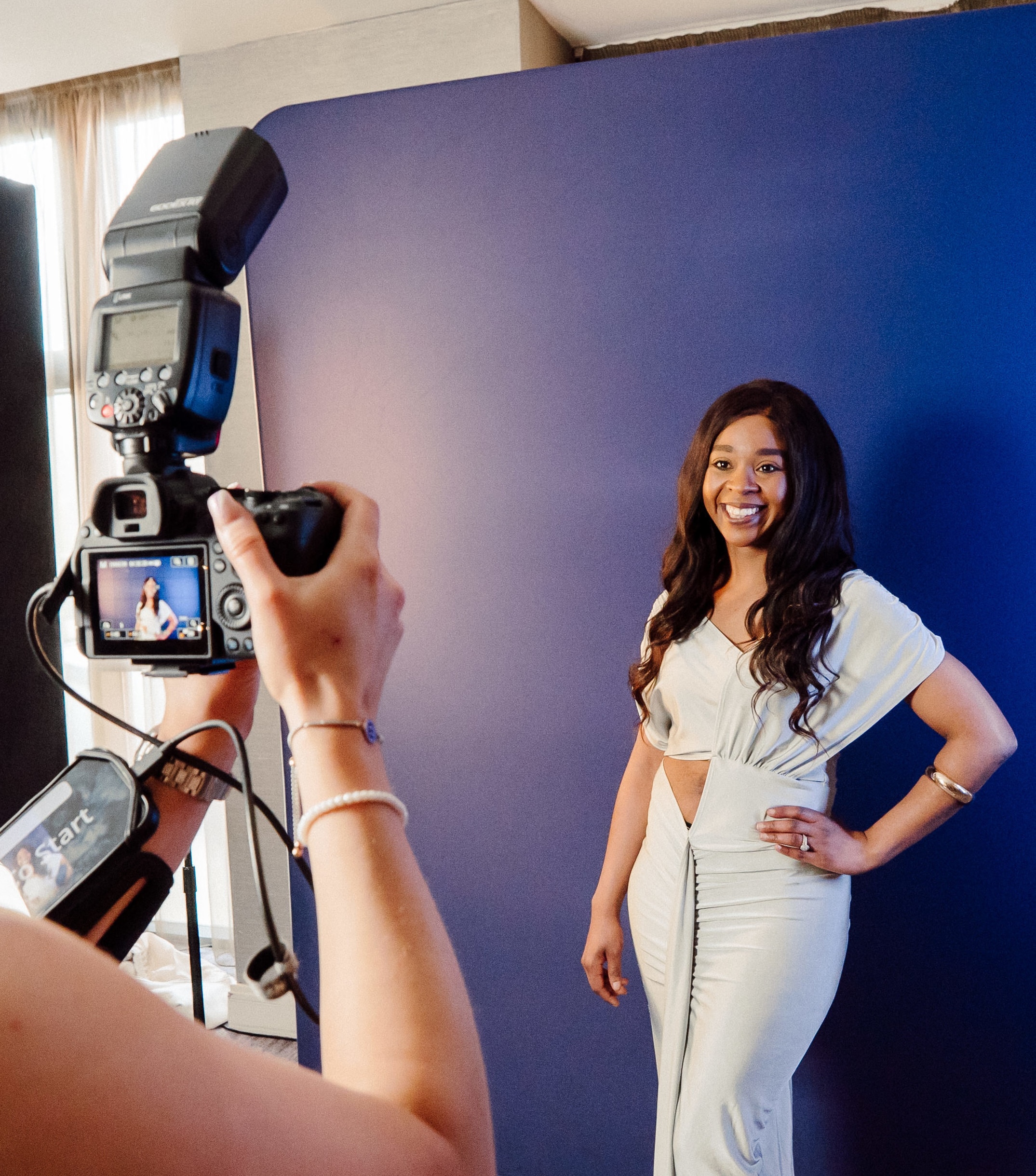Guest being photographed in front of a blue backdrop at a CapCity photo experience
